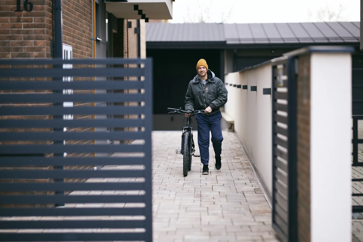 Un homme avec une bicyclette devant un portail alu coulissant
