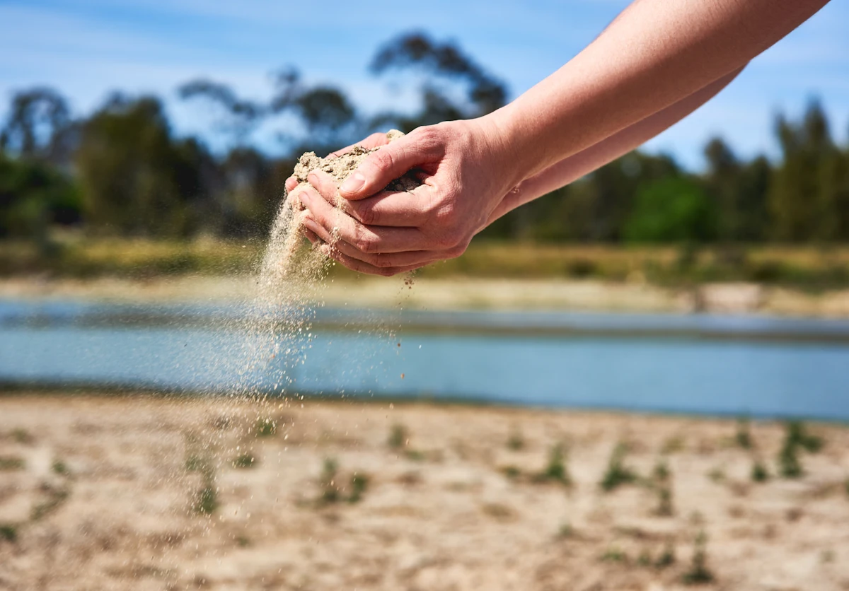 Une personne qui prend du sable de rivière dans ses mains